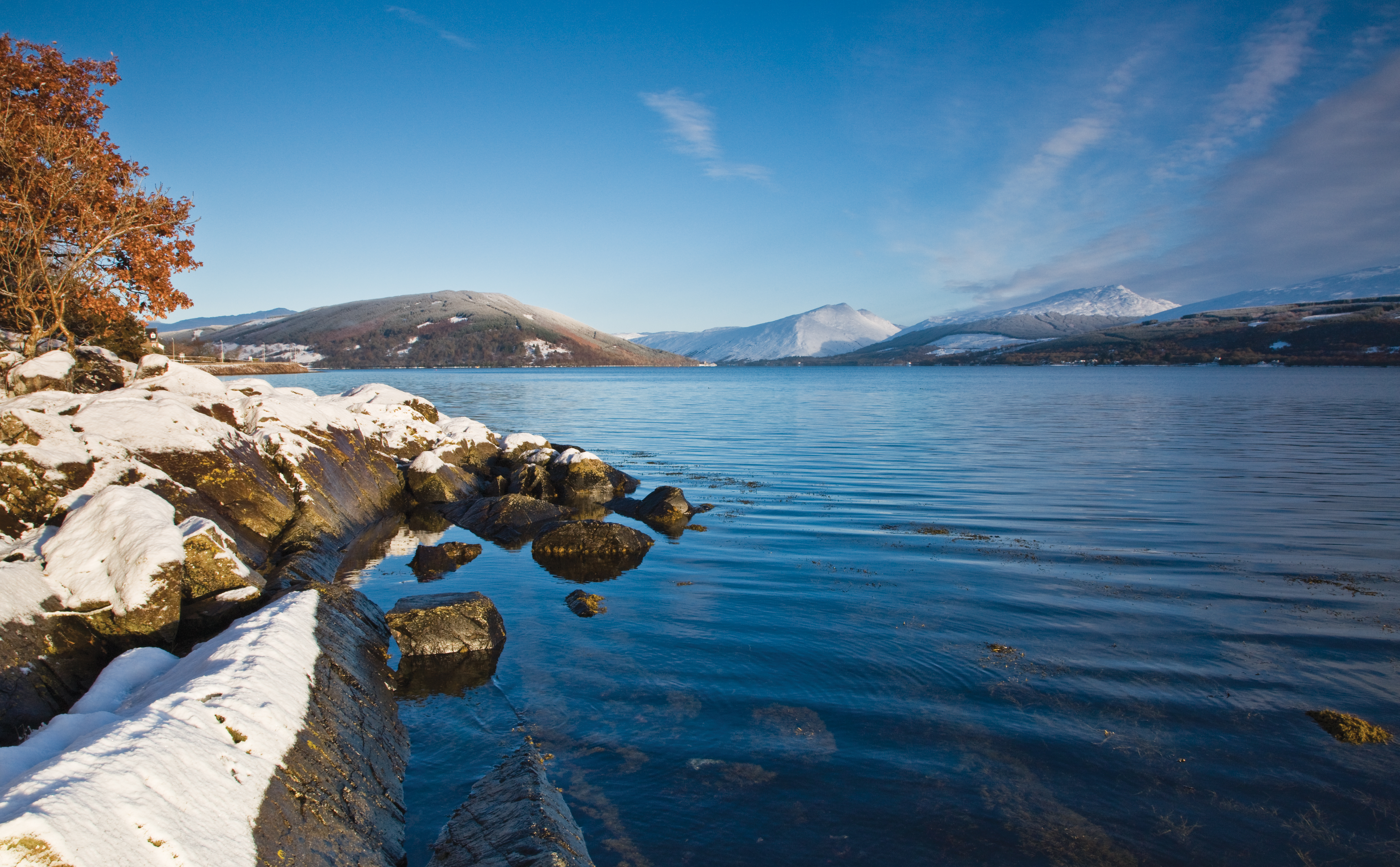 Loch Fyne during winter, showing snow covered banks and trees with auburn leaves.