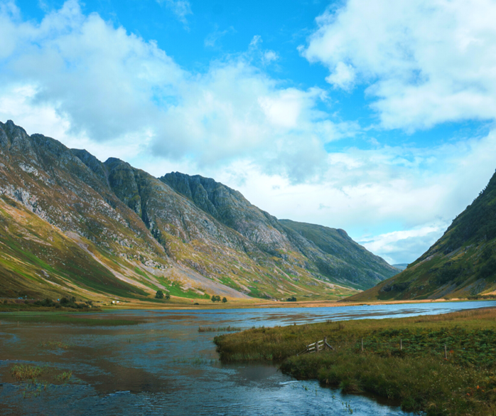 Glencoe Valley during summer, with white clouds in blue sky.